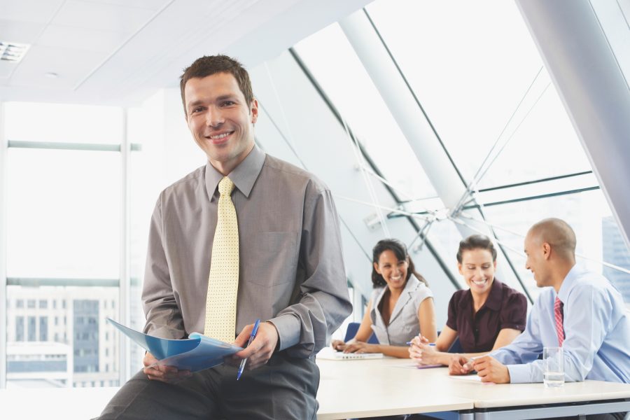 Smiling Business man sitting on conference room table I-style